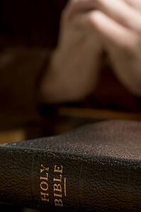 Closeup of Bible with praying hands