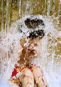 Young boy under waterfall