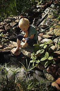 Boy sitting by pond