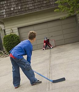 Boys playing hockey on driveway