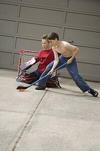 Boys playing hockey on driveway