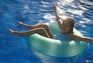 Young girl playing in water on tube