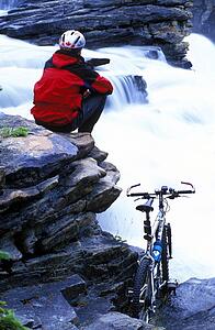 Cyclist taking a break at small waterfalls
