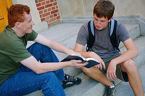 Two young men sitting on steps discussing the Bible