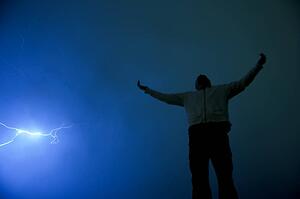 Man with outstretched arms in lightning storm