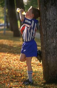 Young soccer player drinking juice