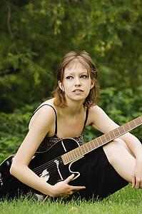 Young woman sitting outside with guitar