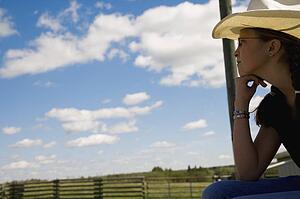 Girl on farm wearing cowboy hat