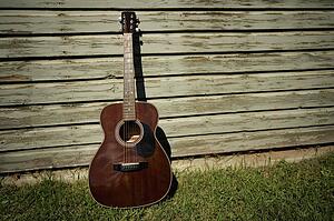 Acoustic guitar leaning against building