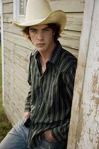 Young man leaning against exterior of worn building