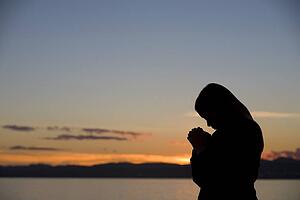 A girl prays at sunset