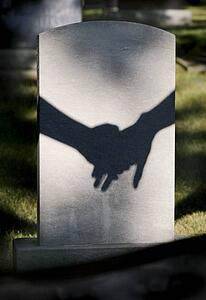 Shadow on tombstone of two clasped hands