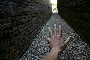 Hand reaching down narrow alley towards light