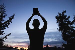 Silhouette of a Bible raised to the heavens