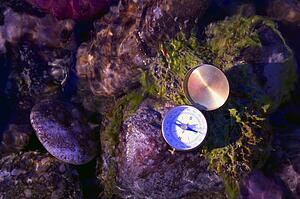 A compass on river rocks