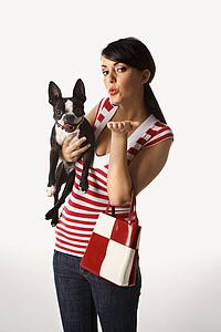 Young adult female Caucasian holding Boston Terrier.