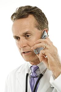 Portrait of a mid-adult Caucasian male doctor with stethoscope around his neck talking on cell phone.