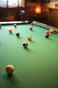 Green billiards table with pool balls spread out.