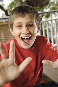 Caucasian teenage boy looking happy and excited reaching hand out.