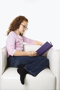 Caucasian female child sitting reading book.