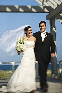 Caucasian mid-adult bride and groom walking together smiling.