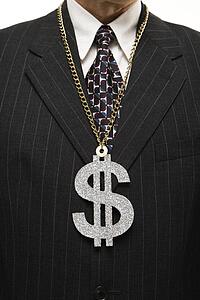 Close-up of Caucasian middle-aged businessman wearing chain necklace with oversized dollar sign.