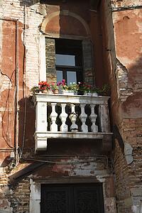 Worn building with balcony and flowers in Venice, Italy.