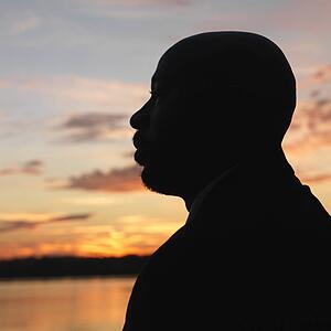 African-American man standing by water at sunset in Washington, D. C., USA.