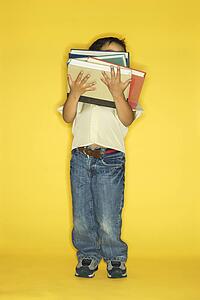 Filipino male child holding stack of books.