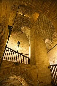 Indoor low angle view of golden masonry structure with arches.