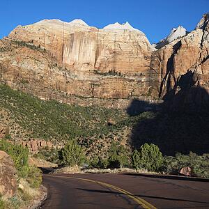Two lane road winding through rocky desert cliffs in Zion National Park, Utah.