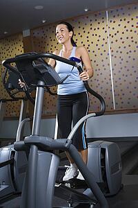 Prime adult Caucasian female on elliptical machine at gym.