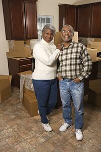 Portrait of middle-aged African-American couple in kitchen with moving boxes.