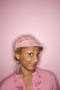 Portrait of young African-American woman on pink background with comical expression on her face.