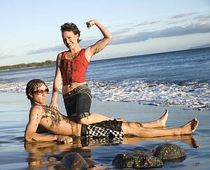 Caucasian young adult couple frolicking on beach.