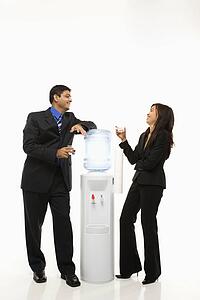 Vietnamese businesswoman and Indian businessman conversing at water cooler.
