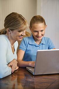 Caucasian mid-adult woman and pre-teen girl using laptop computer.