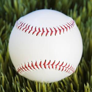 Close-up studio shot of baseball resting in grass.