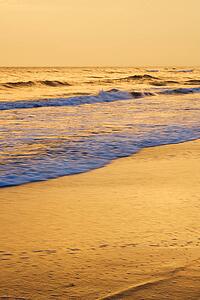 Waves lapping on beach at sunset.
