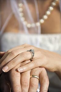 Caucasian mid-adult male and female hands with wedding rings.