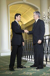 Caucasian prime adult male businessman and Asian prime adult male businessman in hotel.