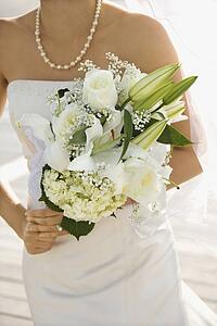 Caucasian mid-adult bride holding flower bouquet.