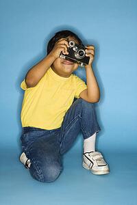 Hispanic male child kneeling with camera.