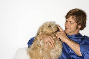 Male Caucasian young adult with fluffy brown dog.