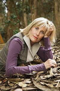 Middle-aged Caucasian woman lying on ground in forest.