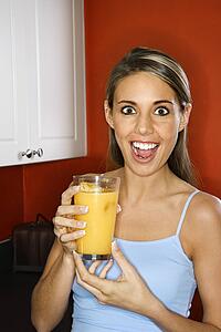 Portrait of young adult woman holding a glass of orange juice.