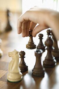Caucasian person hand moving chess piece.