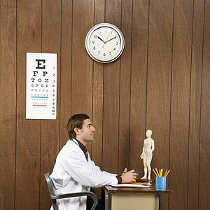 Side view of mid-adult Caucasian male doctor sitting at desk. 
