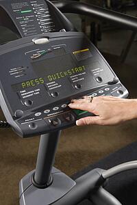Prime adult Caucasian female setting up elliptical machine at gym.