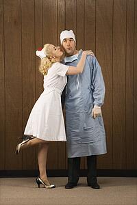 Mid-adult Caucasian female nurse kissing doctor on cheek.